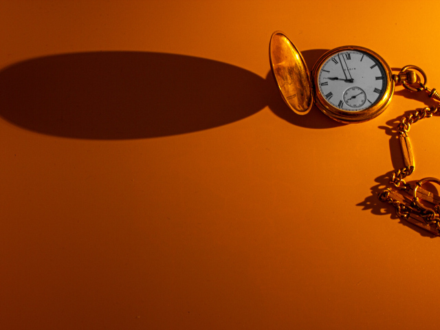 Тень от карманных часов на оранжевом фоне