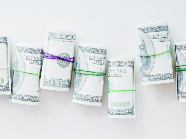 Свертки с долларами на сером фоне