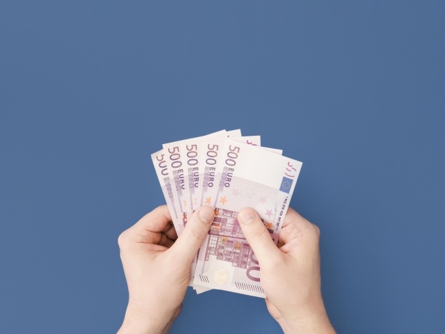 Купюры в пятьсот евро в руках на синем фоне