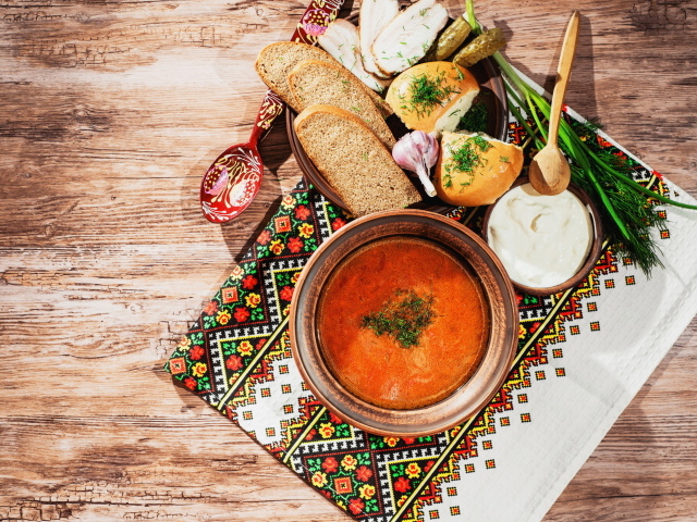 Тарелка борща на столе с салом, хлебом и зеленью