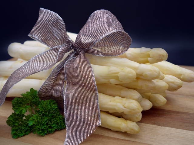 Спаржа с бантом на столе с петрушкой