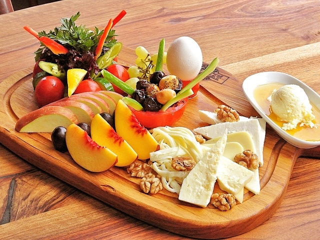 Сыр на доске с фруктами и салатом