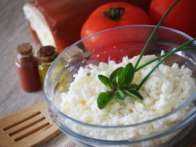 Творог в тарелке на столе с помидорами