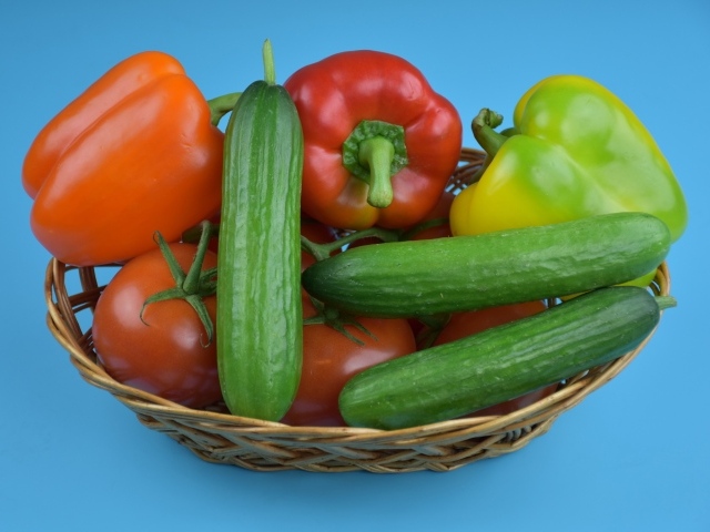 Перец, помидоры и огурцы в корзине на голубом фоне
