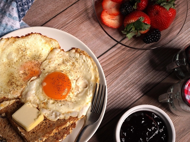 Яичница с гренками на столе с клубникой