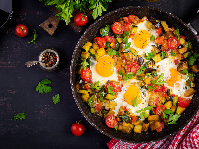 Яичница с овощами в сковороде на столе