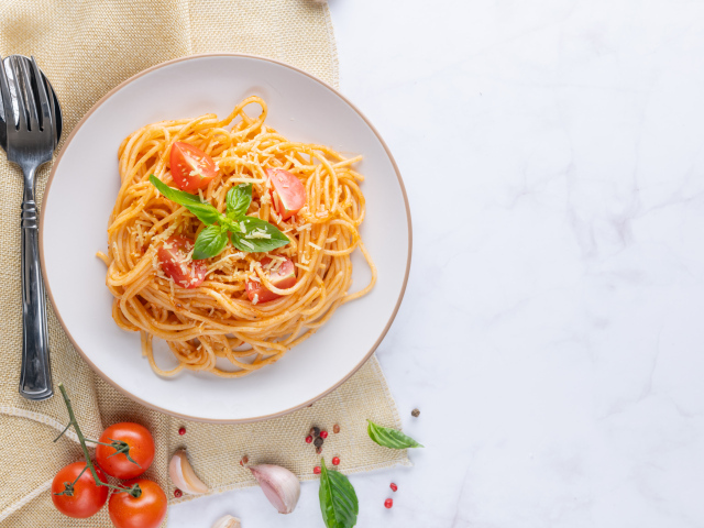 Спагетти с помидорами в тарелке на столе
