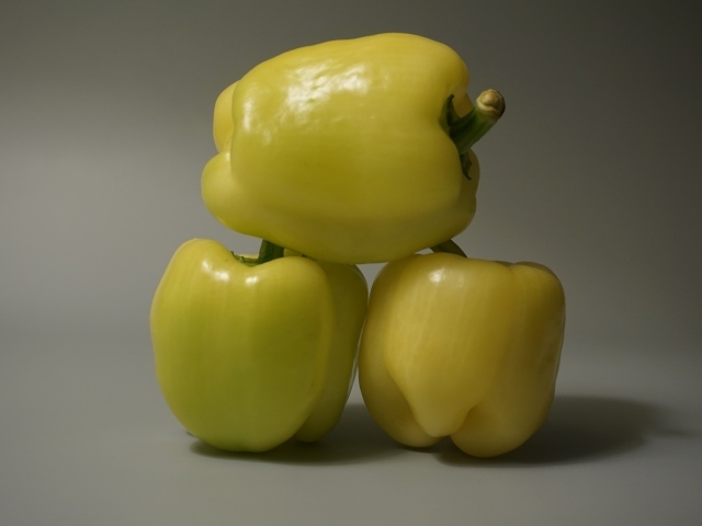 Три желтых перца на сером фоне