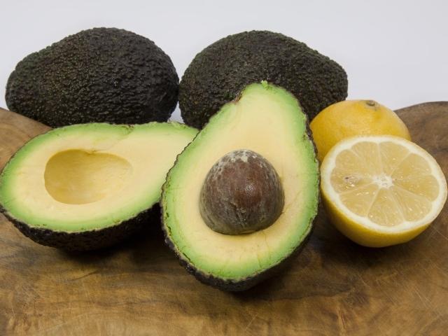 Авокадо на столе с половинками лимона