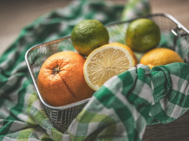 Цитрусовые фрукты в железной корзинке на столе