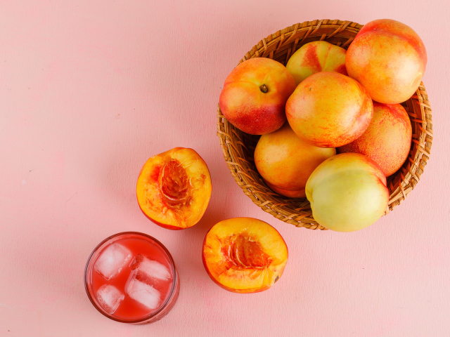 Свежий нектарин в корзине на розовом столе