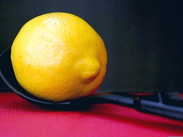 Большой желтый лимон на чайной ложке