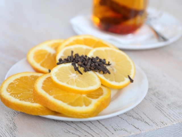 Лимон и апельсин с гвоздикой на тарелке