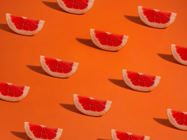 Кусочки грейпфрута на оранжевом фоне