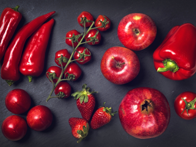 Красные овощи и фрукты на сером столе