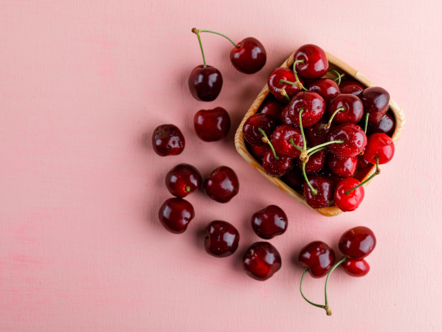 Спелые сладкие красные черешни на розовом фоне