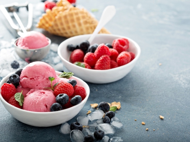 Сладкие ягоды с шариками мороженого на столе