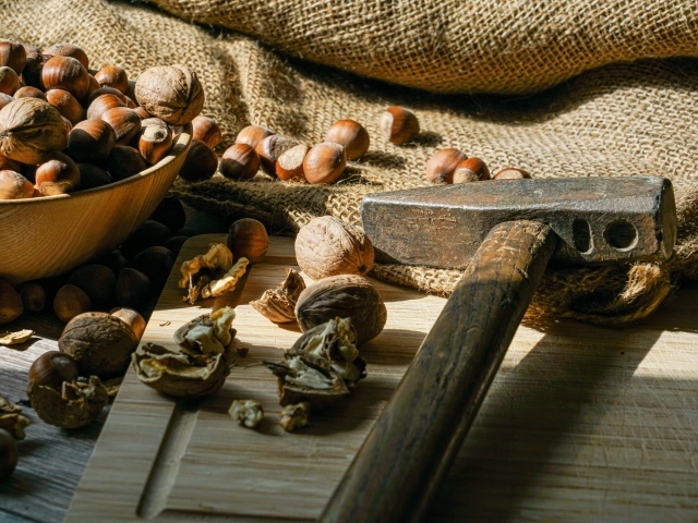 Грецкие орехи и фундук на столе с молотком