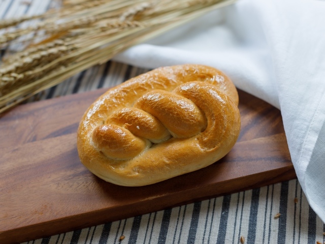 Булочка на столе с колосьями пшеницы