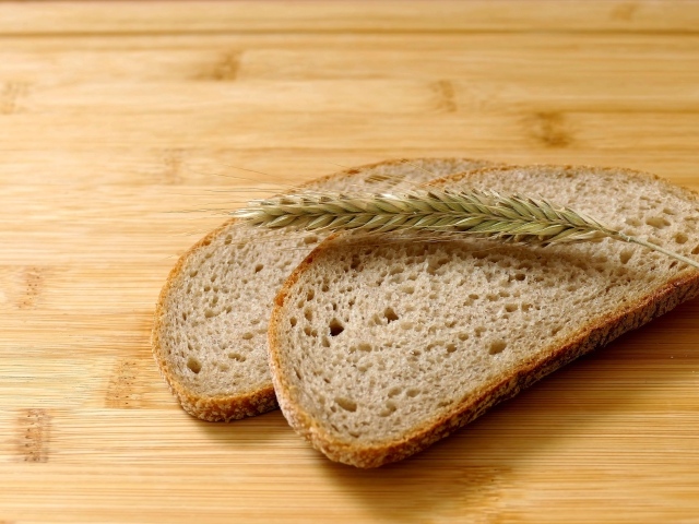 Два куска хлеба с колоском на деревянном столе