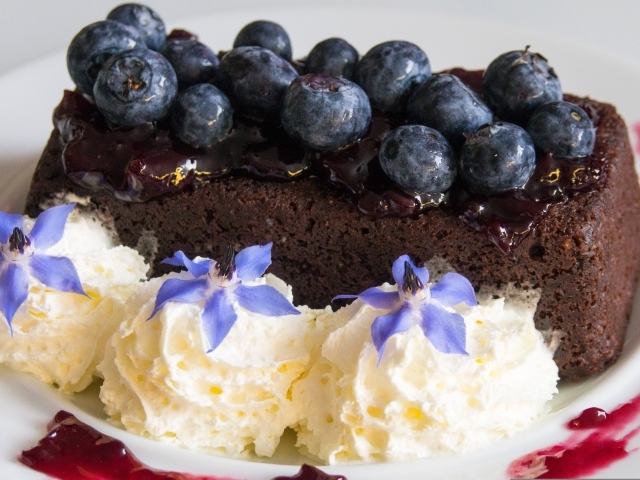 Шоколадный торт с черникой на тарелке со взбитыми сливками