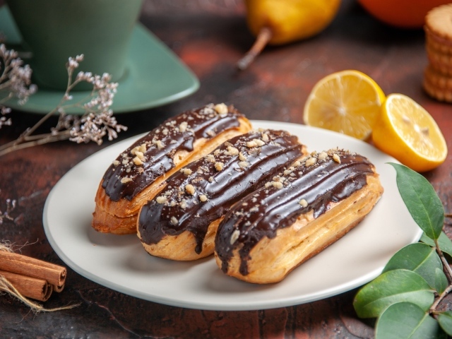 Эклеры на тарелке с корицей и апельсинами