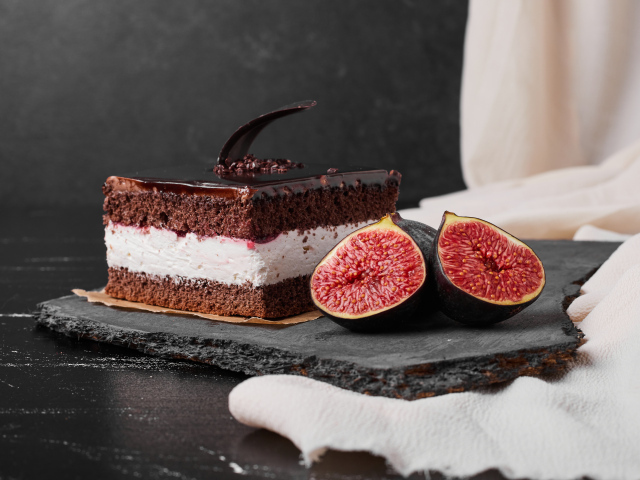 Кусок шоколадного торта с половинками инжира на столе