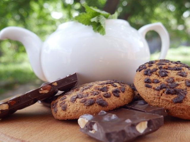 Чайник на столе с печеньем и шоколадом