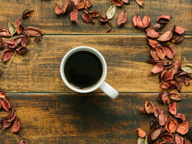 Чашка кофе с опавшими листьями на деревянном столе