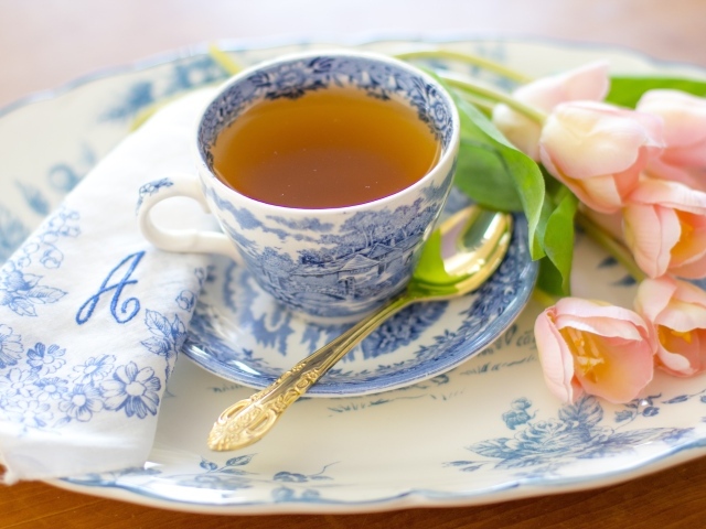 Чашка чая на тарелке с розовыми тюльпанами
