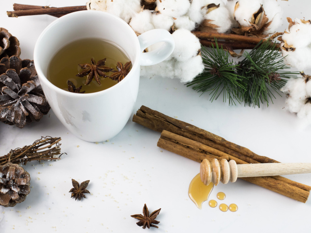 Чашка чая со специями на столе с хлопком и шишками