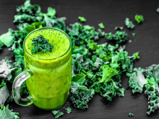 Бокал с зеленым смузи с листьями