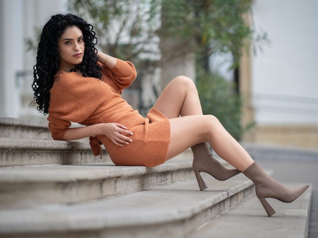 Девушка в теплом платье лежит на ступеньках