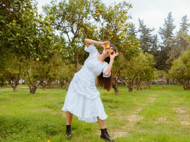 Девушка в белом платье закрыла глаза лимонами