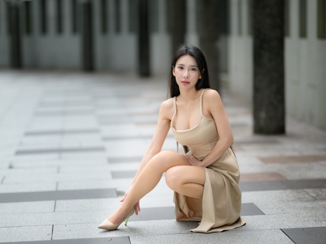 Девушка азиатка в платье сидит на корточках