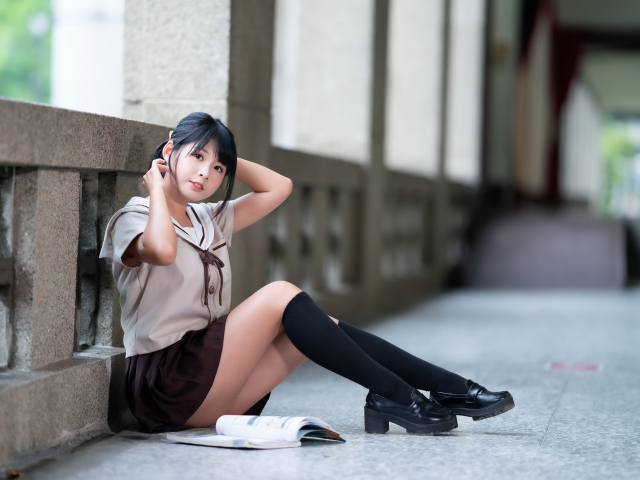 Девушка азиатка в школьной форме сидит на полу