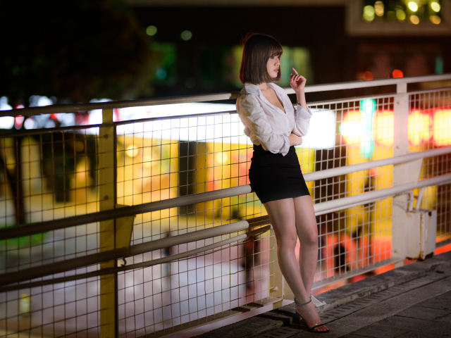 Азиатка в короткой черной юбке позирует для фото