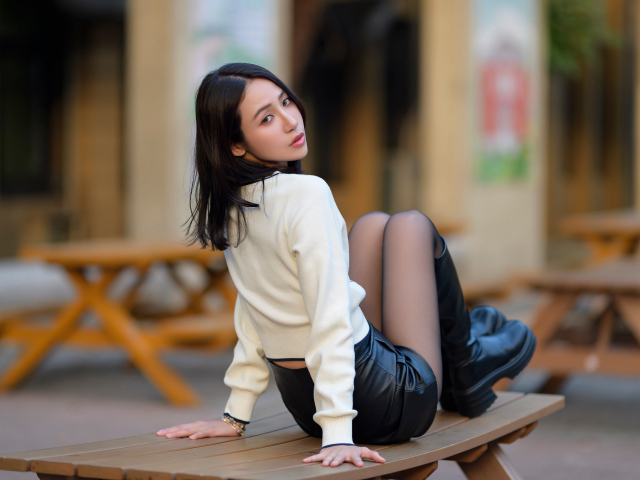 Азиатка в сапогах сидит на столе