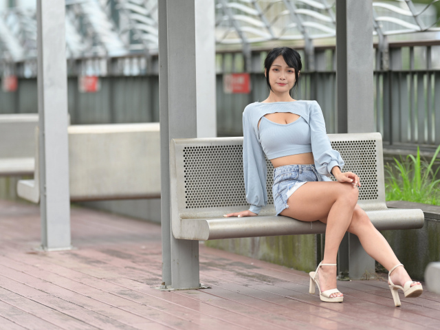 Красивая темноволосая девушка азиатка сидит на лавке