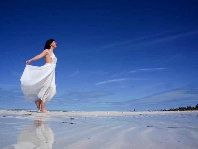 Красивая девушка в белом платье на мокром песке