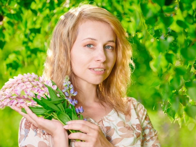 Красивая девушка с цветами люпина в руке