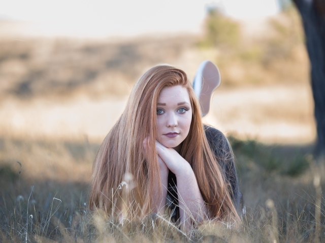 Красивая рыжеволосая девушка лежит на траве