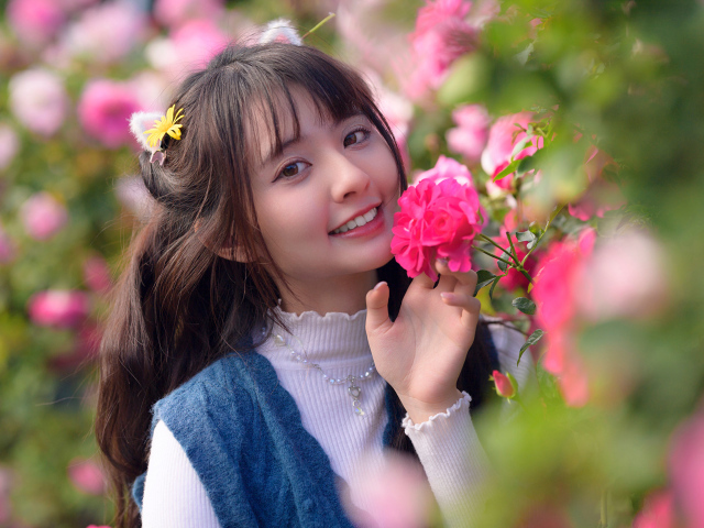 Красивая улыбающаяся азиатка с розовым цветком розы