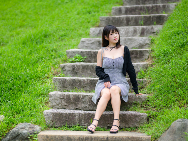 Красивая молодая девушка азиатка сидит на ступеньках