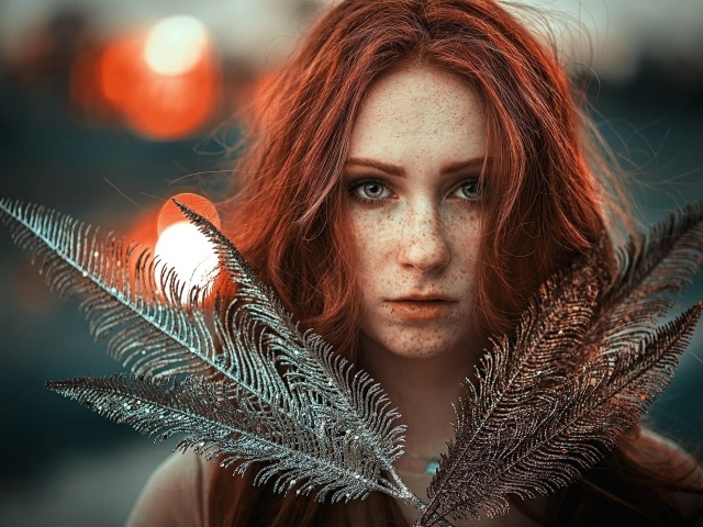 Яркая рыжеволосая девушка с перьями в руках