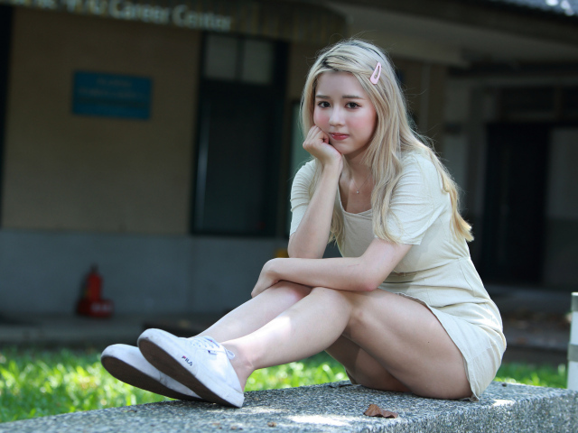 Милая азиатка сидит на холодном бетоне