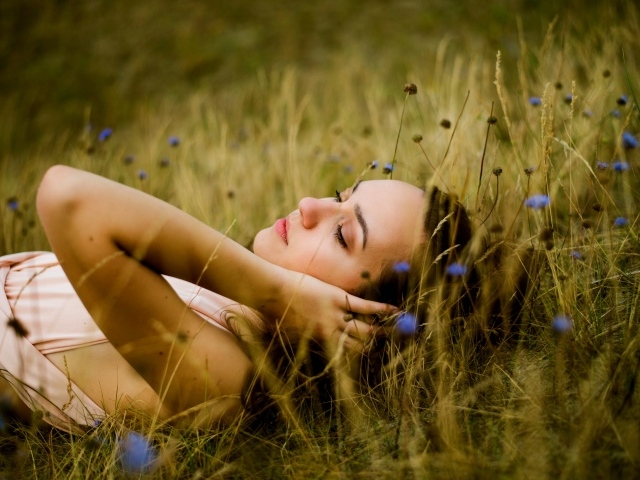 Милая девушка лежит на траве на поле