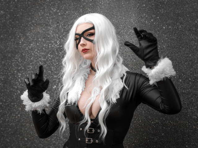 Девушка в белом парике в черном костюме у серой стены