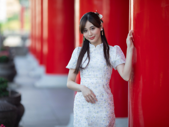 Длинноволосая азиатка позирует у красной колонны