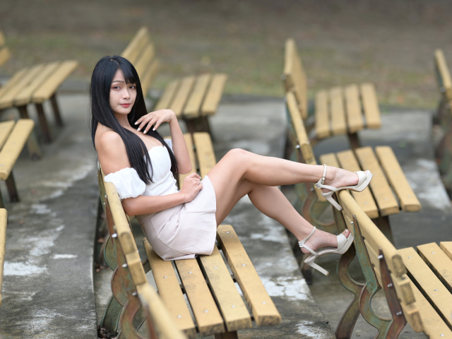 Длинноволосая азиатка сидит на деревянной лавке